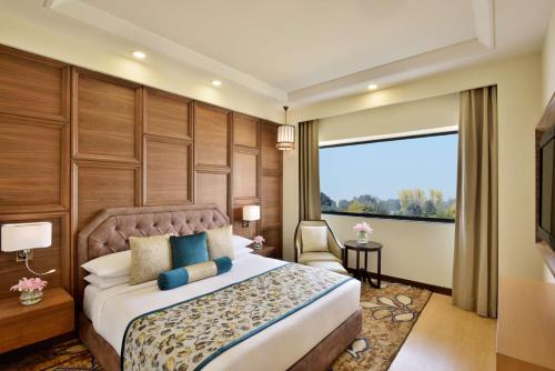 a hotel room with a bed and a large window at Radisson Srinagar in Srinagar