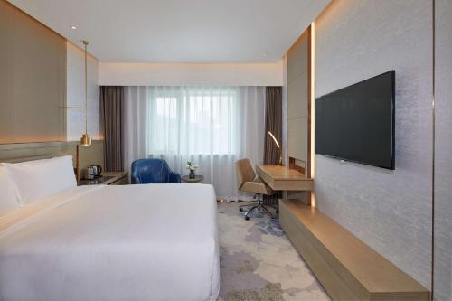 a hotel room with a bed and a desk and a television at Park Plaza Beijing Science Park in Beijing