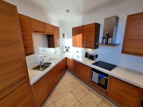 una cocina con armarios de madera y fregadero en Luxury 2 bedroom city centre apartment with panoramic views and high ceilings, en Aberdeen