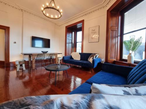 a living room with a blue couch and a table at Luxury 2 bedroom city centre apartment with panoramic views and high ceilings in Aberdeen
