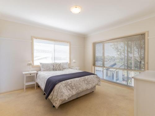 a bedroom with a bed and a large window at Sea Breeze, 1,23 Stubby St Nelson Bay - Pet Friendly duplex with boat parking, air con and wi-fi in Nelson Bay