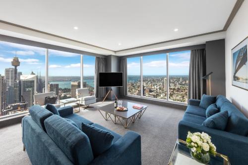 a living room with blue couches and large windows at Meriton Suites World Tower, Sydney in Sydney