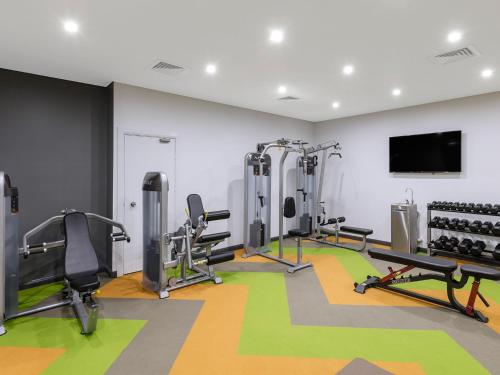 a gym with tread machines and a flat screen tv at Meriton Suites World Tower, Sydney in Sydney