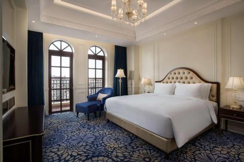 um quarto com uma cama grande e uma cadeira azul em Radisson Blu Forest Manor Shanghai Hongqiao em Xangai