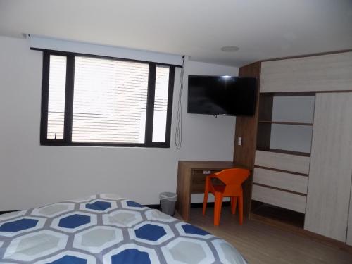 a bedroom with a bed and a window and a chair at Terrazas in Bogotá