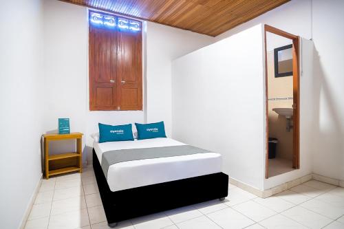 a bedroom with a bed with blue pillows on it at Ayenda Acacia in Ibagué