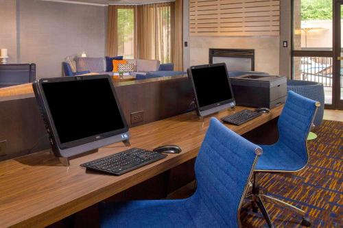 an office with two computers on a desk with blue chairs at Sonesta Select Durham Research Triangle Park in Durham