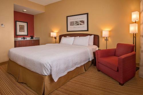 a hotel room with a bed and a red chair at Sonesta Select Durham Research Triangle Park in Durham