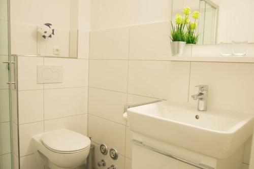 a white bathroom with a toilet and a sink at Haus-am-Deich-Wohnung-11 in Dahme