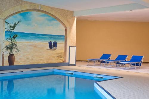 a swimming pool with blue chairs and a painting of the beach at Les Hameaux De Lozere Sure Hotel Collection by Best Western in Fournels