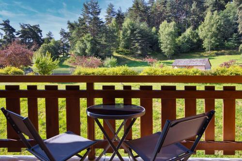 two chairs and a table on a wooden fence at Les Hameaux De Lozere Sure Hotel Collection by Best Western in Fournels