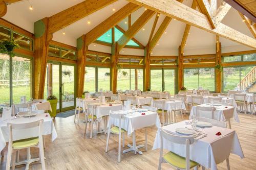 a dining room with white tables and chairs at Les Hameaux De Lozere Sure Hotel Collection by Best Western in Fournels