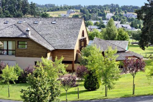a large house in a residential neighborhood with trees at Les Hameaux De Lozere Sure Hotel Collection by Best Western in Fournels