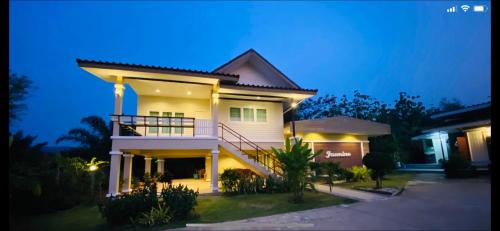 a large white house with a balcony at night at Panutsaya Homestay in Wang Nam Khieo