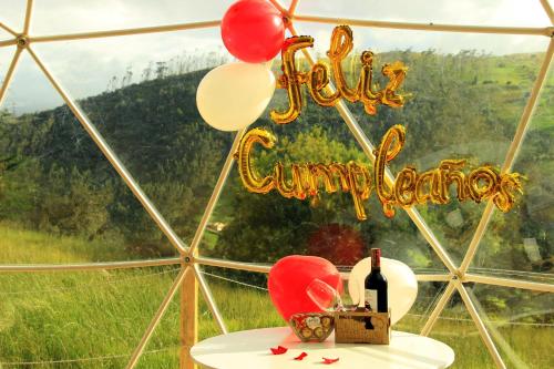 a table with a bottle of wine and balloons at Glamping Caliza La Calera in La Calera