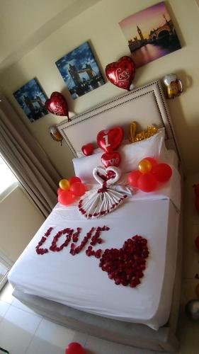 a bedroom with a white bed with red flowers on it at Rm Staycation TaalView Smdc in Tagaytay