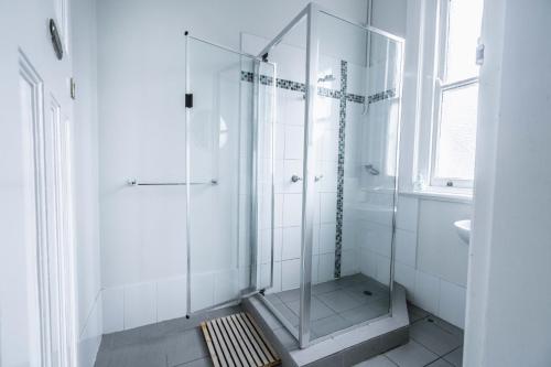 La salle de bains blanche est pourvue d'une douche et d'un lavabo. dans l'établissement The Oriental Hotel, à Newcastle