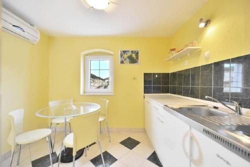 a kitchen with yellow walls and a table and chairs at Holiday home Žarko - 50m from the sea in Pučišća