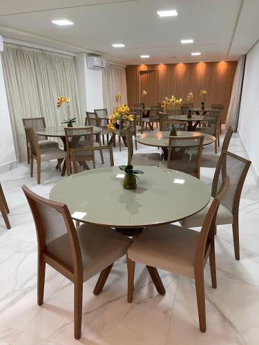 a dining room with tables and chairs and flowers at Buenos Ayres Flats, Cabo Branco 1qto cozinha completa in João Pessoa
