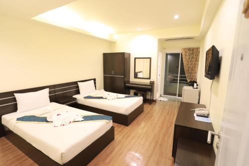 a hotel room with two beds and a desk at Platinum Place in Bangkok