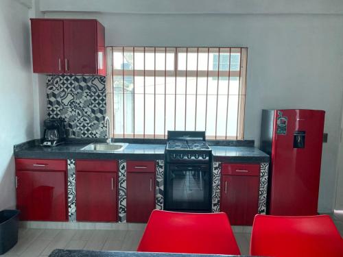 une cuisine avec des placards rouges, une cuisinière et des chaises rouges dans l'établissement Lidxi Angela, à Juchitán de Zaragoza