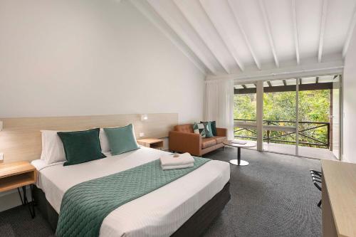 a bedroom with a large bed and a large window at Avoca Beach Hotel in Avoca Beach