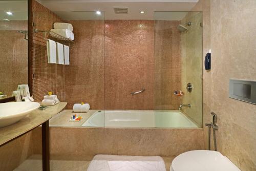 a bathroom with a tub and a sink at Radisson Jass Hotel, Khajuraho in Khajurāho