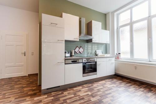 una cucina con elettrodomestici bianchi e pavimenti in legno di WR Grüne Ferienwohnung in der alten Apotheke a Wernigerode
