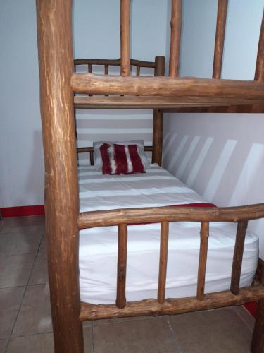 a wooden bunk bed with white sheets and a pillow at Hostal Blood Moon in Rio Dulce