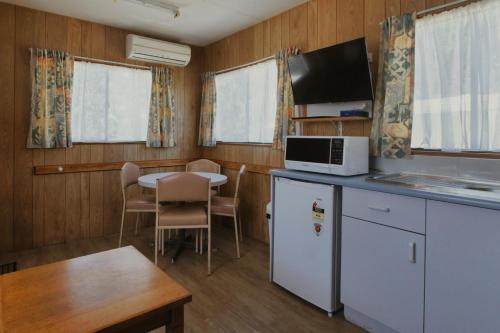 a kitchen and dining room with a table and a microwave at Woodmans Hill Motel in Ballarat