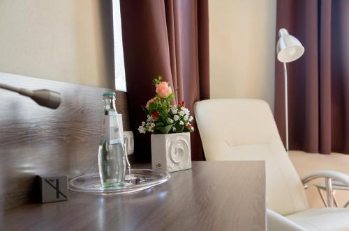 Una mesa con una botella y flores. en Hotel - Restaurant Kastanienhof Lauingen, en Lauingen