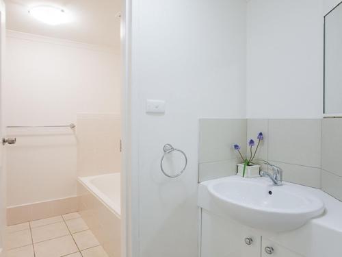 a white bathroom with a sink and a shower at Bay Parklands 23 located at Little Beach with air con pool and tennis court in Shoal Bay