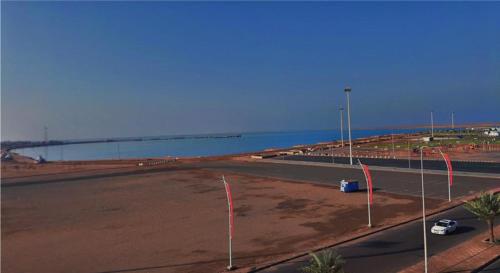 un estacionamiento vacío junto al océano con un puente en الشاطئ الأبيض للشقق المخدومة en Rayyis