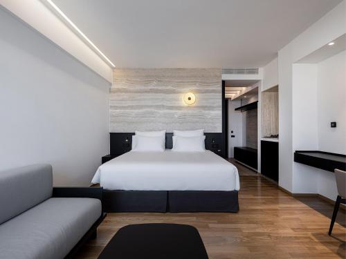 a bedroom with a white bed and a couch at The Tanneries Hotel & Spa - a Member of Design Hotels in Chania Town