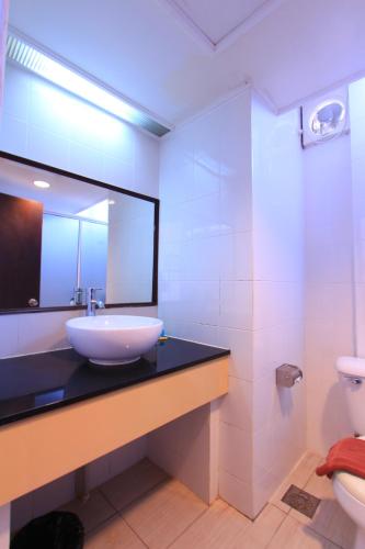 a bathroom with a sink and a mirror and a toilet at Telang Usan Hotel Kuching in Kuching