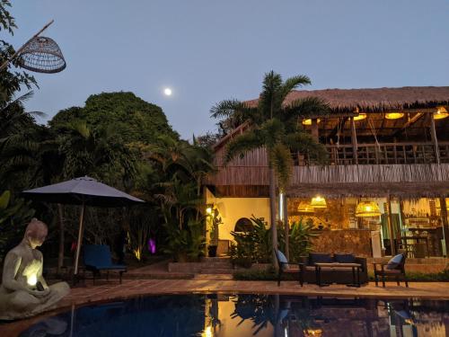 a pool in front of a resort with a statue next to it at Raingsey Bungalow in Kep