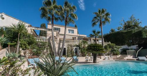 une maison avec des palmiers et une piscine dans l'établissement Juan Les Pins Near Cannes Beaches 18-20 Guests, à Antibes