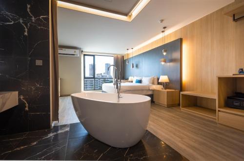 a bathroom with a tub and a bedroom with a bed at 56 Hotel in Bangna