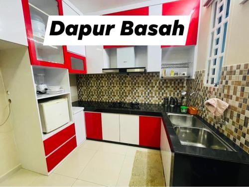 a kitchen with red and white cabinets and a sink at No 11 Nazirin Homestay Tmn Desa Manjung Lumut in Lumut