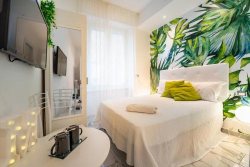 una camera da letto con un letto bianco e un murale tropicale sul muro di ORA BLU Guest house a Santa Margherita Ligure