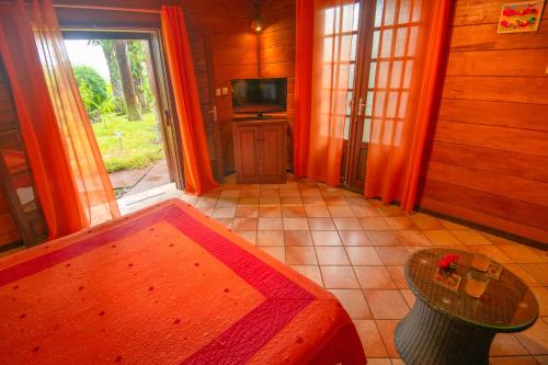 Zimmer mit einem Tisch und einem TV in einem Haus in der Unterkunft Baobab et Palmiers in L’Étang-Salé