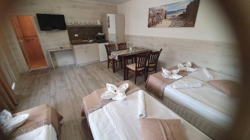 a room with two beds and a table and a kitchen at Family Hotel Kedara in Burgas City
