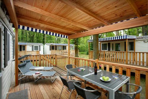 KNAUS Campingpark Hamburg في هامبورغ: سطح خشبي عليه طاولة وكراسي