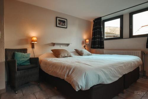 a bedroom with a large bed and a chair at Le vieux Sanglier - 41 pers - Malmedy in Malmedy