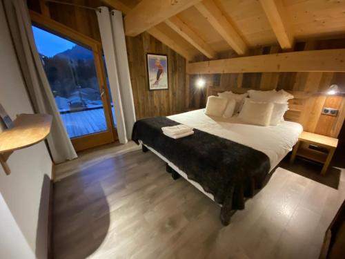 a bedroom with a bed and a large window at Chalet Azalée, Montriond, Morzine, Avoriaz in Montriond