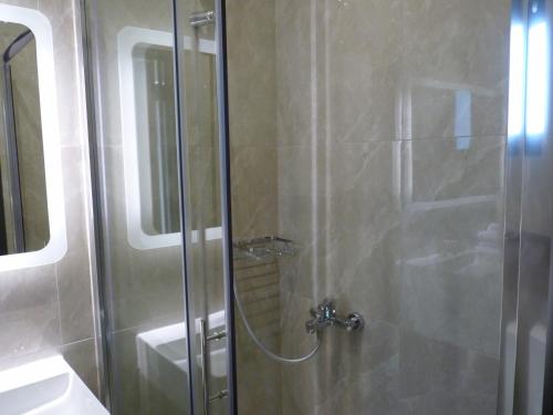 a shower with a glass door next to a sink at Comfort Suites & Rooms in Larisa