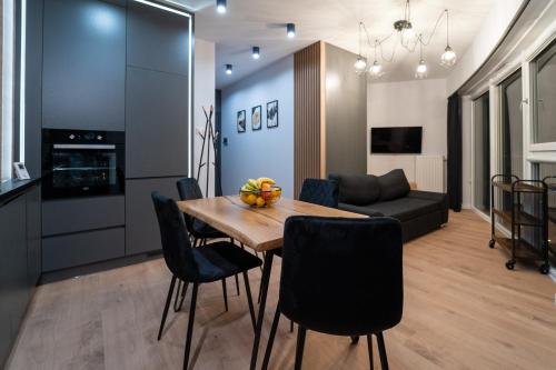 cocina y sala de estar con mesa de madera y sillas en Panorama Capital Tito - 16 piętro en Rzeszów