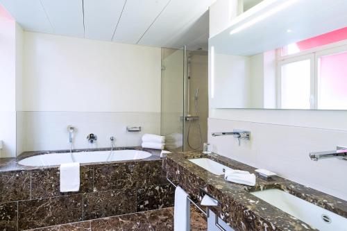 a bathroom with a large tub and a large mirror at Hotel St.Gotthard in Zürich