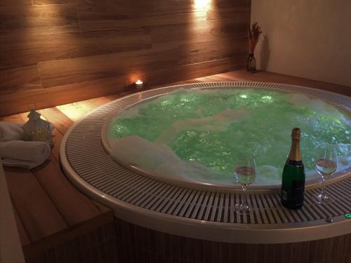 a hot tub with a bottle of wine and two wine glasses at Penzion Bačalský mlýn in Morašice