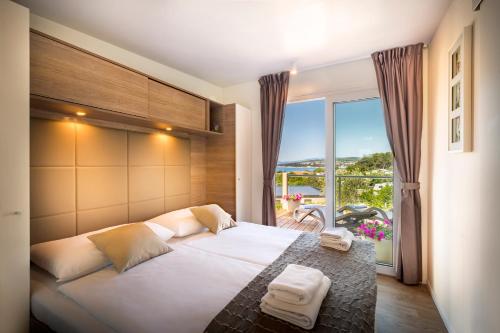 a bedroom with a large bed with a large window at Valamar Camping Krk in Krk